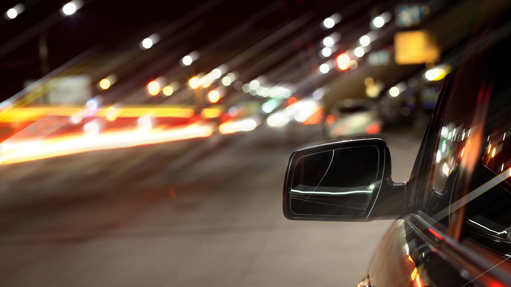 Image of a busy road at night, the lights are blurred and glare. This represents how a person with keratoconus might view the scene.